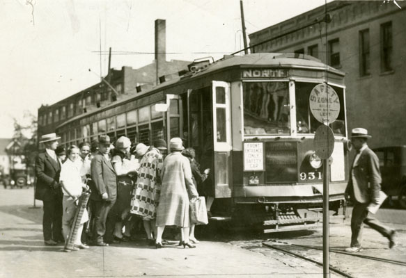 A streetcar with several people lined up to board.