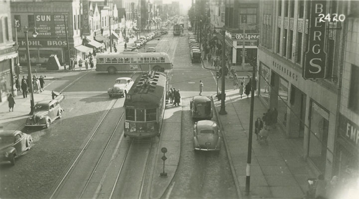 View looking down on a busy intersection with streetcars, cars, and pedestrians.